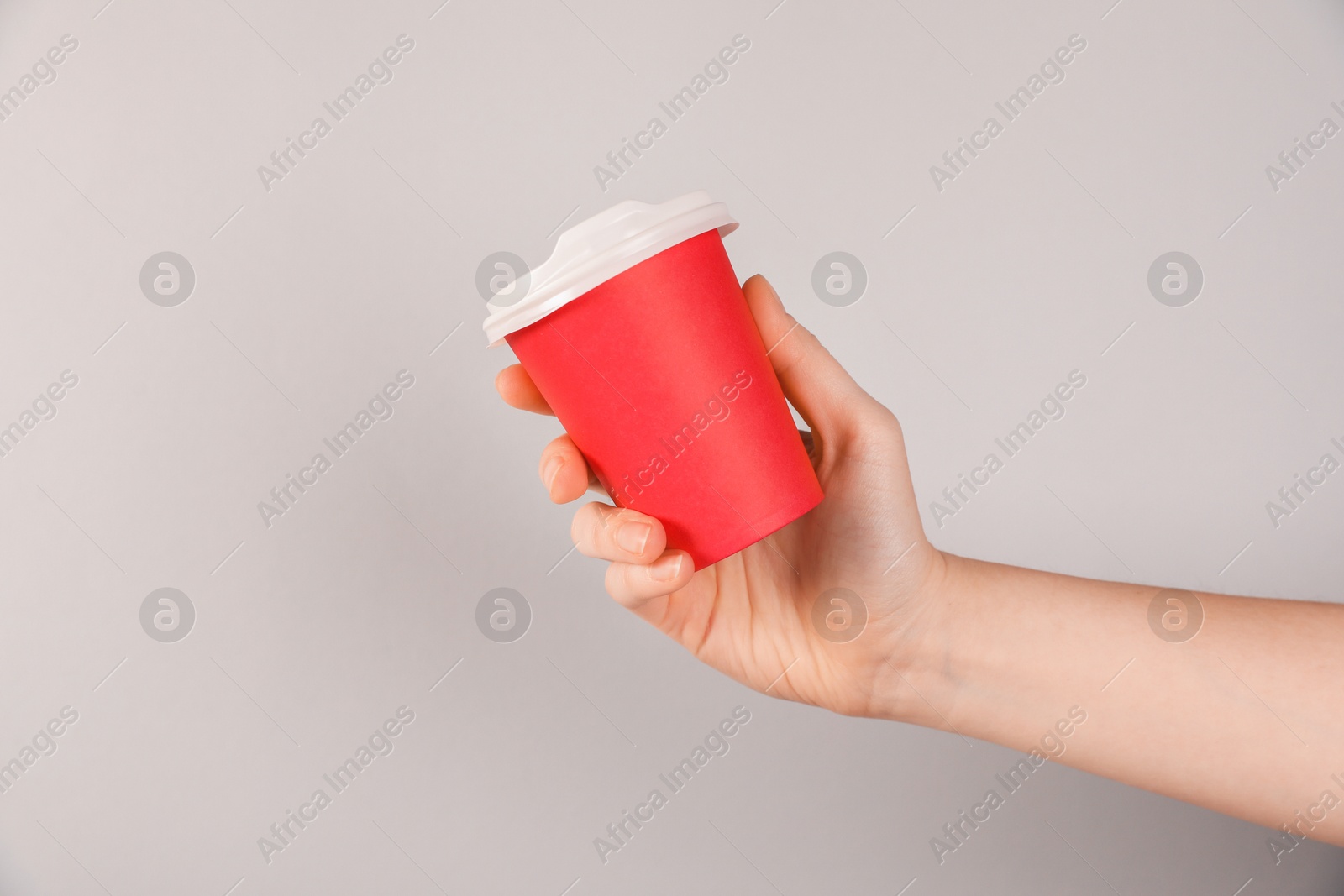 Woman holding paper cup on grey background, closeup. Mockup for design Photo of Woman holding paper cup on grey background, closeup. Mockup for design
