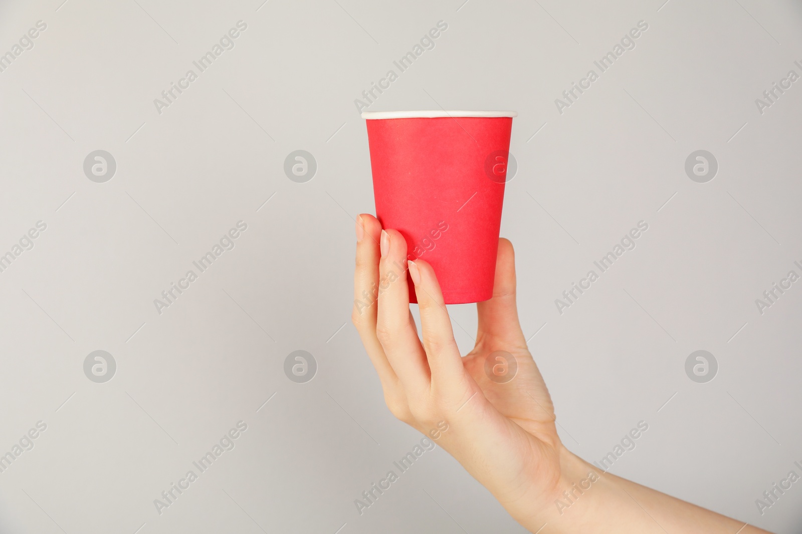 Woman holding paper cup on grey background, closeup. Mockup for design Photo of Woman holding paper cup on grey background, closeup. Mockup for design
