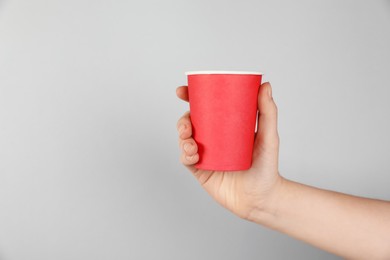 Photo of Woman holding paper cup on grey background, closeup. Mockup for design