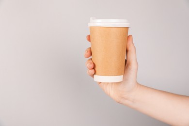 Photo of Woman holding paper cup on grey background, closeup. Mockup for design