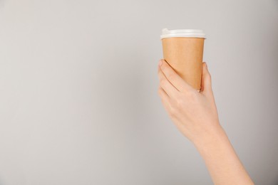 Photo of Woman holding paper cup on grey background, closeup. Mockup for design