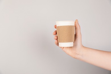 Photo of Woman holding paper cup on grey background, closeup. Mockup for design