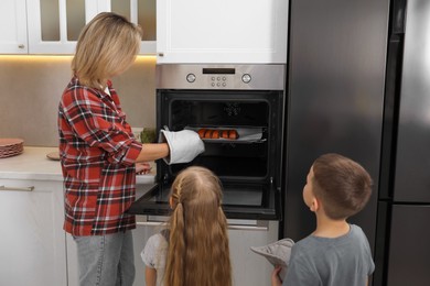 Photo of Little helpers. Children baking with their mother at home