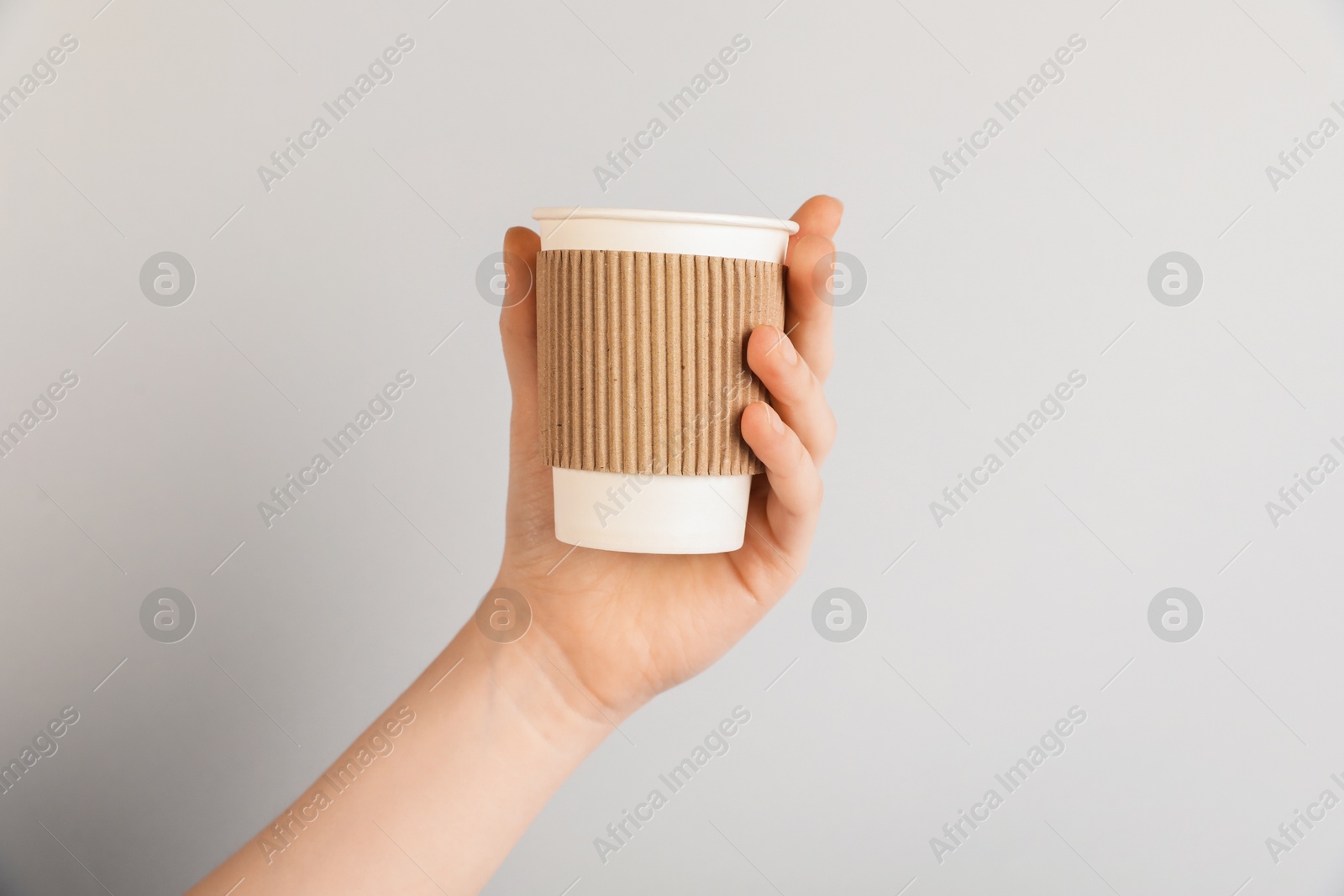 Woman holding paper cup on grey background, closeup. Mockup for design Photo of Woman holding paper cup on grey background, closeup. Mockup for design