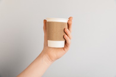 Photo of Woman holding paper cup on grey background, closeup. Mockup for design