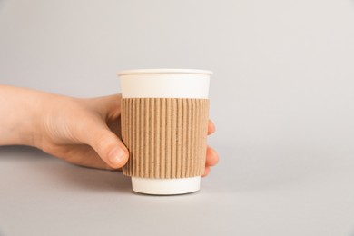 Photo of Woman holding paper cup on grey background, closeup. Mockup for design