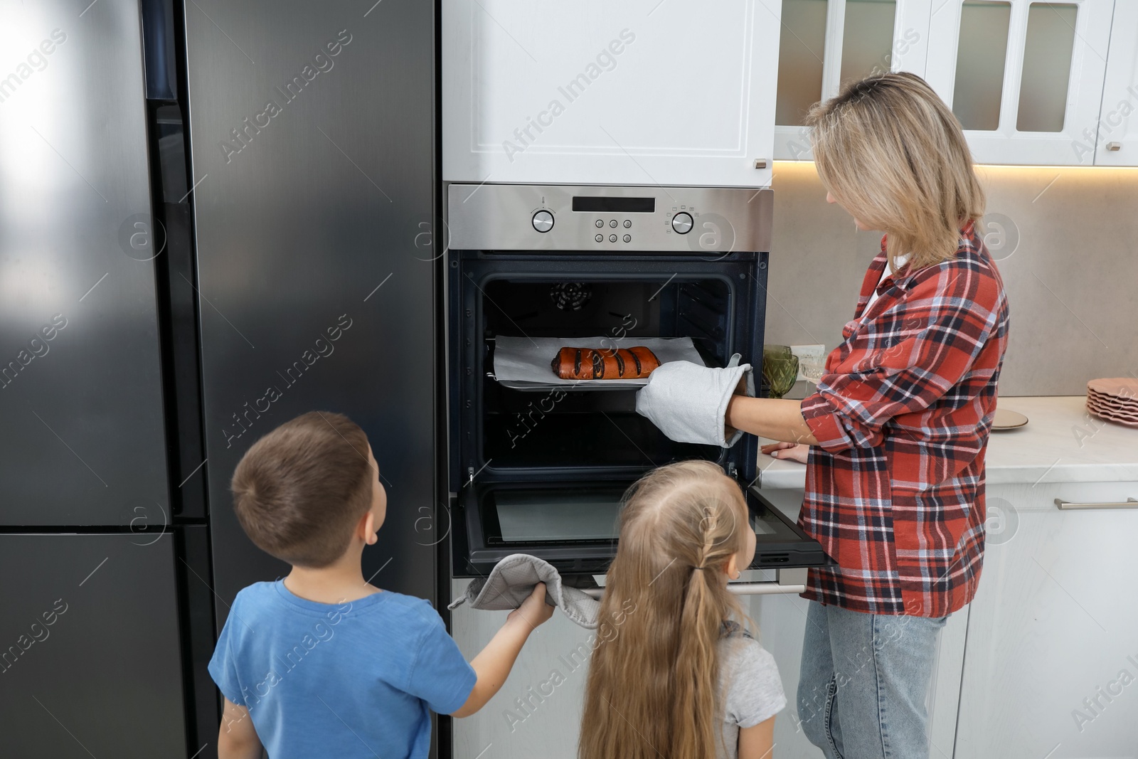 Photo of Little helpers. Children baking with their mother at home