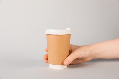 Photo of Woman holding paper cup on grey background, closeup. Mockup for design