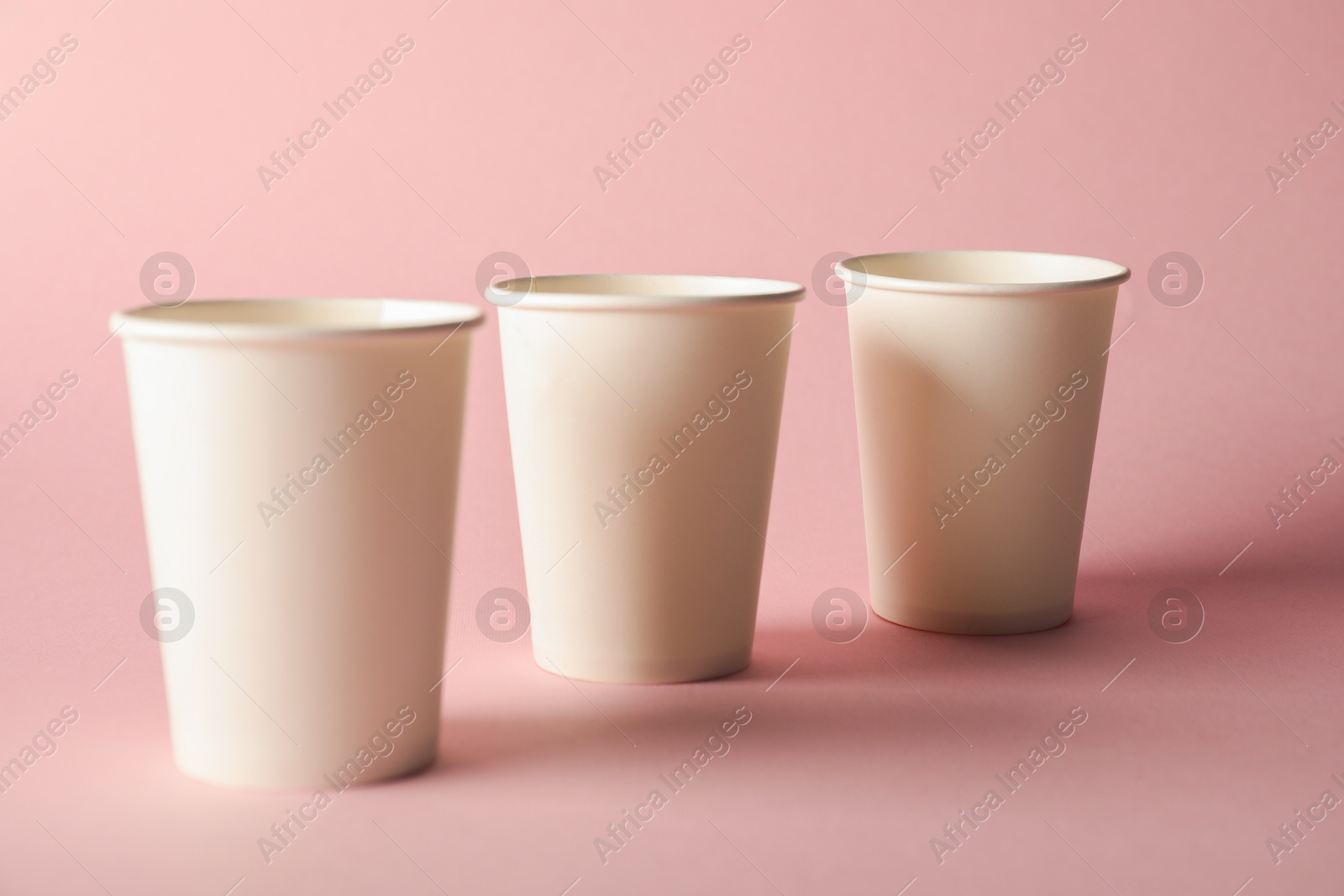 Paper cups on pink background, closeup. Mockup for design Photo of Paper cups on pink background, closeup. Mockup for design