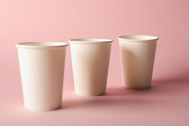 Photo of Paper cups on pink background, closeup. Mockup for design
