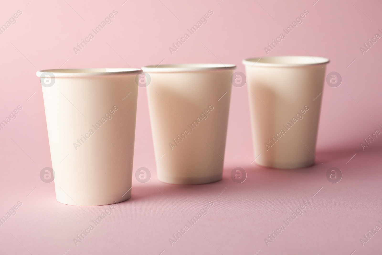 Paper cups on pink background, closeup. Mockup for design Photo of Paper cups on pink background, closeup. Mockup for design