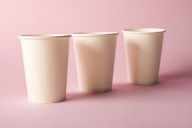 Photo of Paper cups on pink background, closeup. Mockup for design