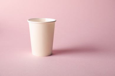 Photo of One paper cup on pink background. Mockup for design