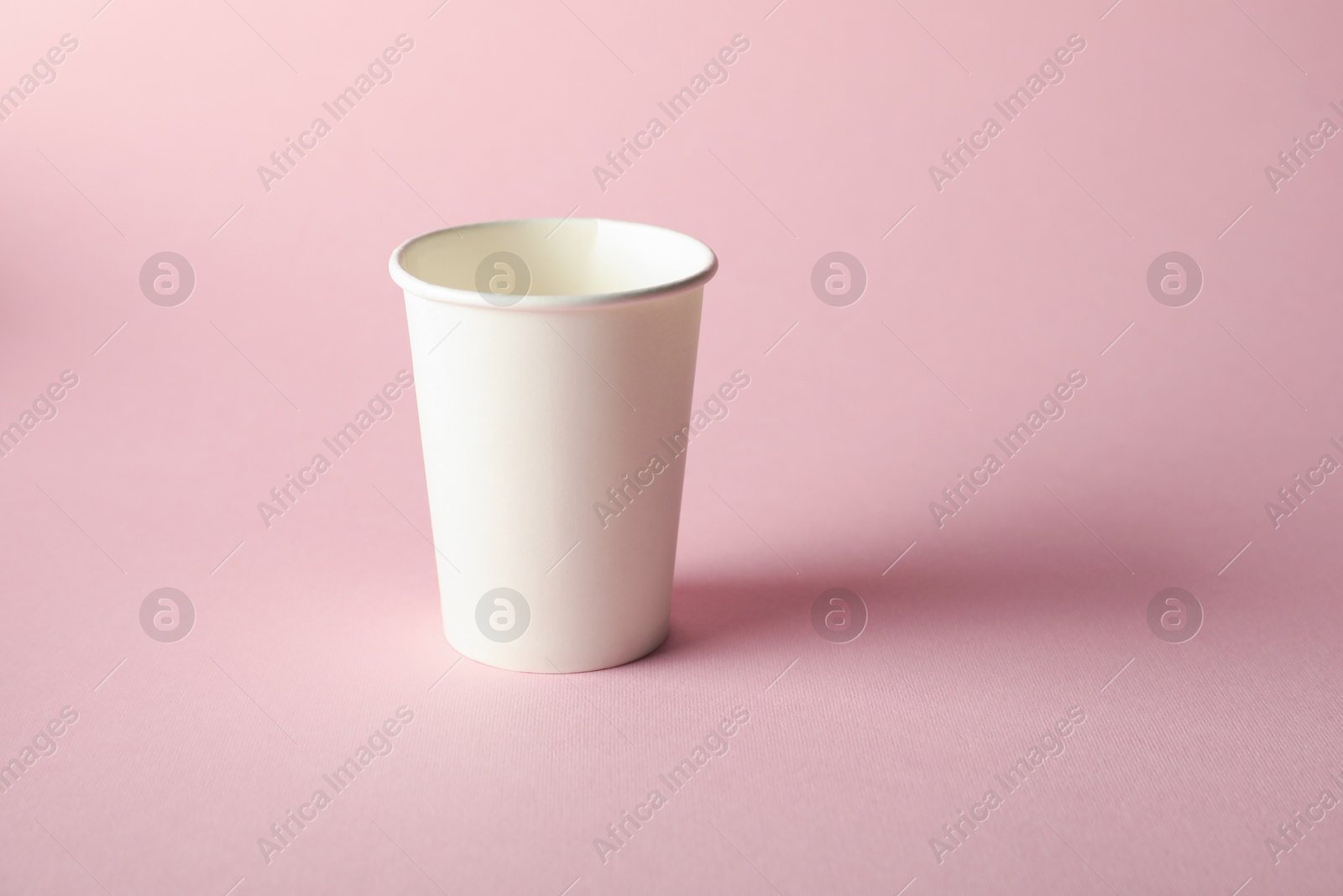 One paper cup on pink background. Mockup for design Photo of One paper cup on pink background. Mockup for design