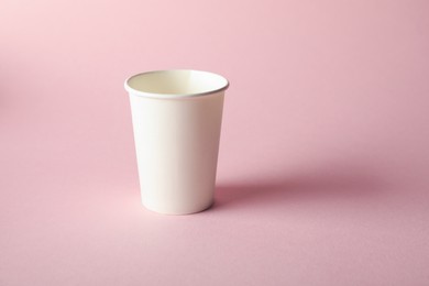 Photo of One paper cup on pink background. Mockup for design