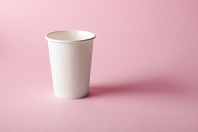 Photo of One paper cup on pink background. Mockup for design