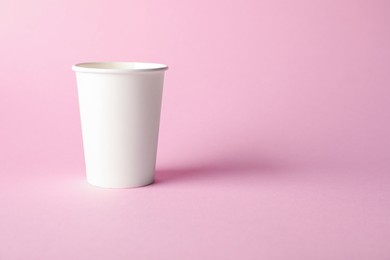 Photo of One paper cup on pink background. Mockup for design
