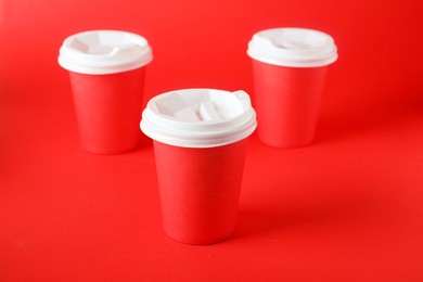 Photo of Paper cups on red background, closeup. Mockup for design