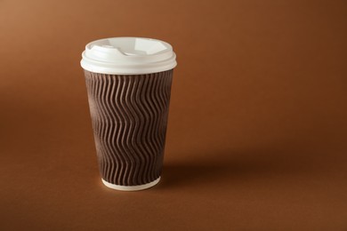 Photo of One paper cup on brown background. Mockup for design