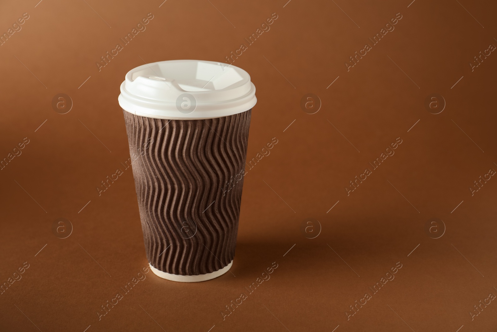 One paper cup on brown background. Mockup for design Photo of One paper cup on brown background. Mockup for design