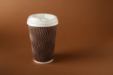 Photo of One paper cup on brown background. Mockup for design