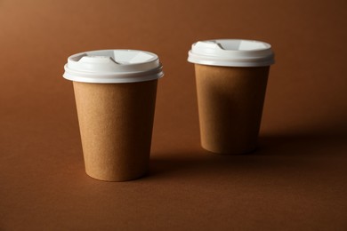 Photo of Paper cups with lids on brown background. Mockup for design