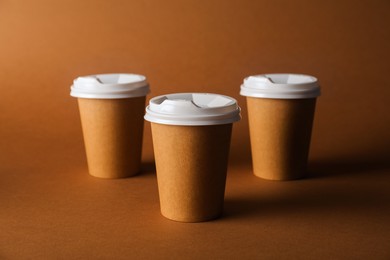 Photo of Paper cups with lids on brown background. Mockup for design
