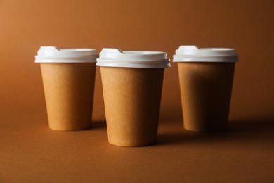 Photo of Paper cups with lids on brown background. Mockup for design