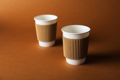 Photo of Paper cups on brown background, selective focus. Mockup for design
