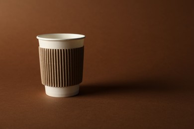 Photo of One paper cup on brown background. Mockup for design