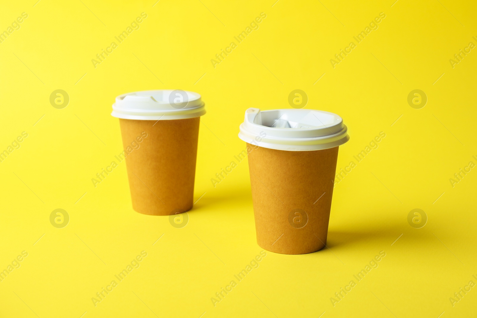 Paper cups on yellow background. Mockup for design Photo of Paper cups on yellow background. Mockup for design