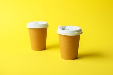 Photo of Paper cups on yellow background. Mockup for design