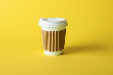 Photo of One paper cup on yellow background. Mockup for design