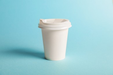 Photo of One paper cup on light blue background. Mockup for design