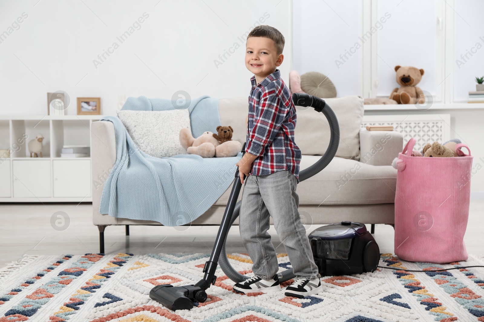 Photo of Little helper. Cute boy vacuuming at home