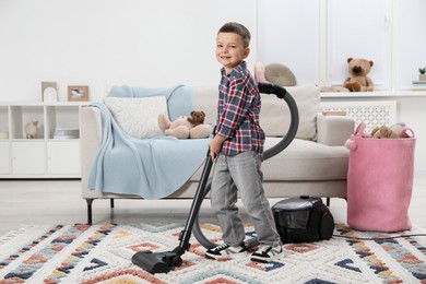 Photo of Little helper. Cute boy vacuuming at home