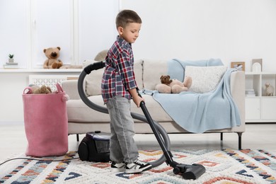 Photo of Little helper. Cute boy vacuuming at home