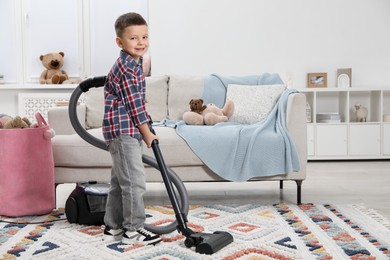 Photo of Little helper. Cute boy vacuuming at home