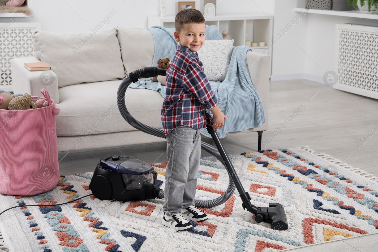 Photo of Little helper. Cute boy vacuuming at home