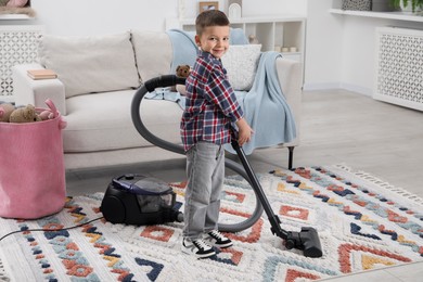 Photo of Little helper. Cute boy vacuuming at home