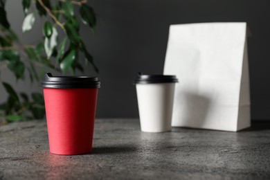 Photo of Paper cups on grey textured table indoors, selective focus. Mockup for design