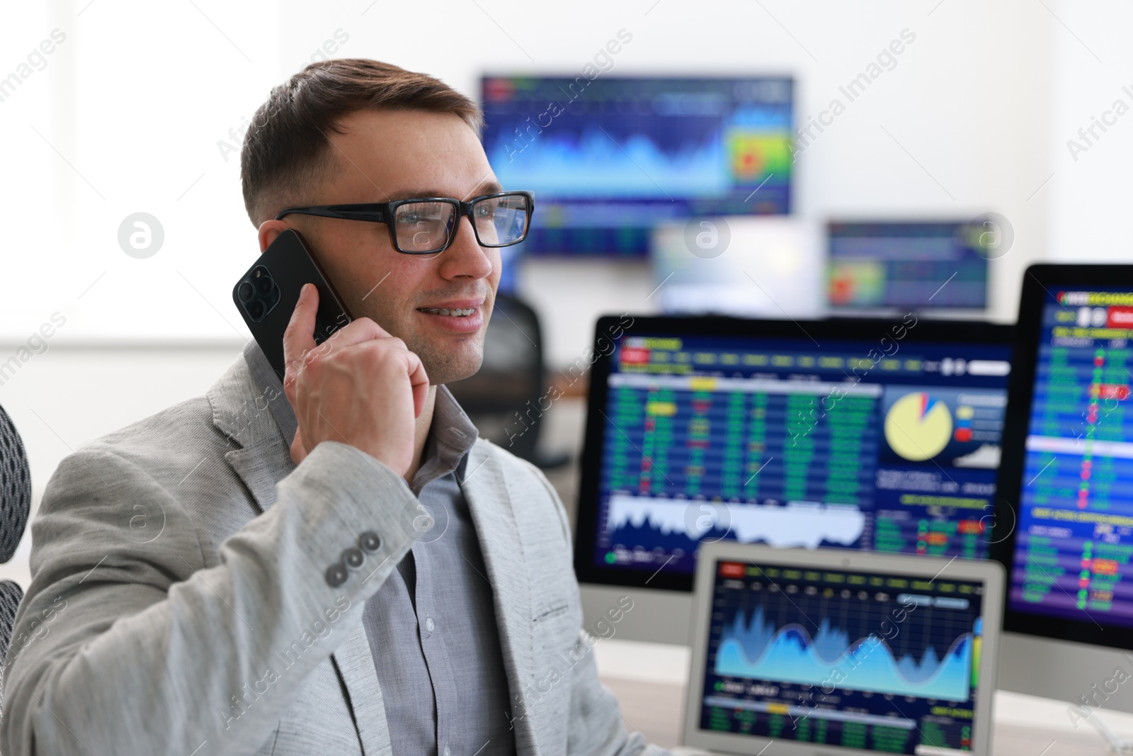 Photo of Financial trading specialist talking on phone in office