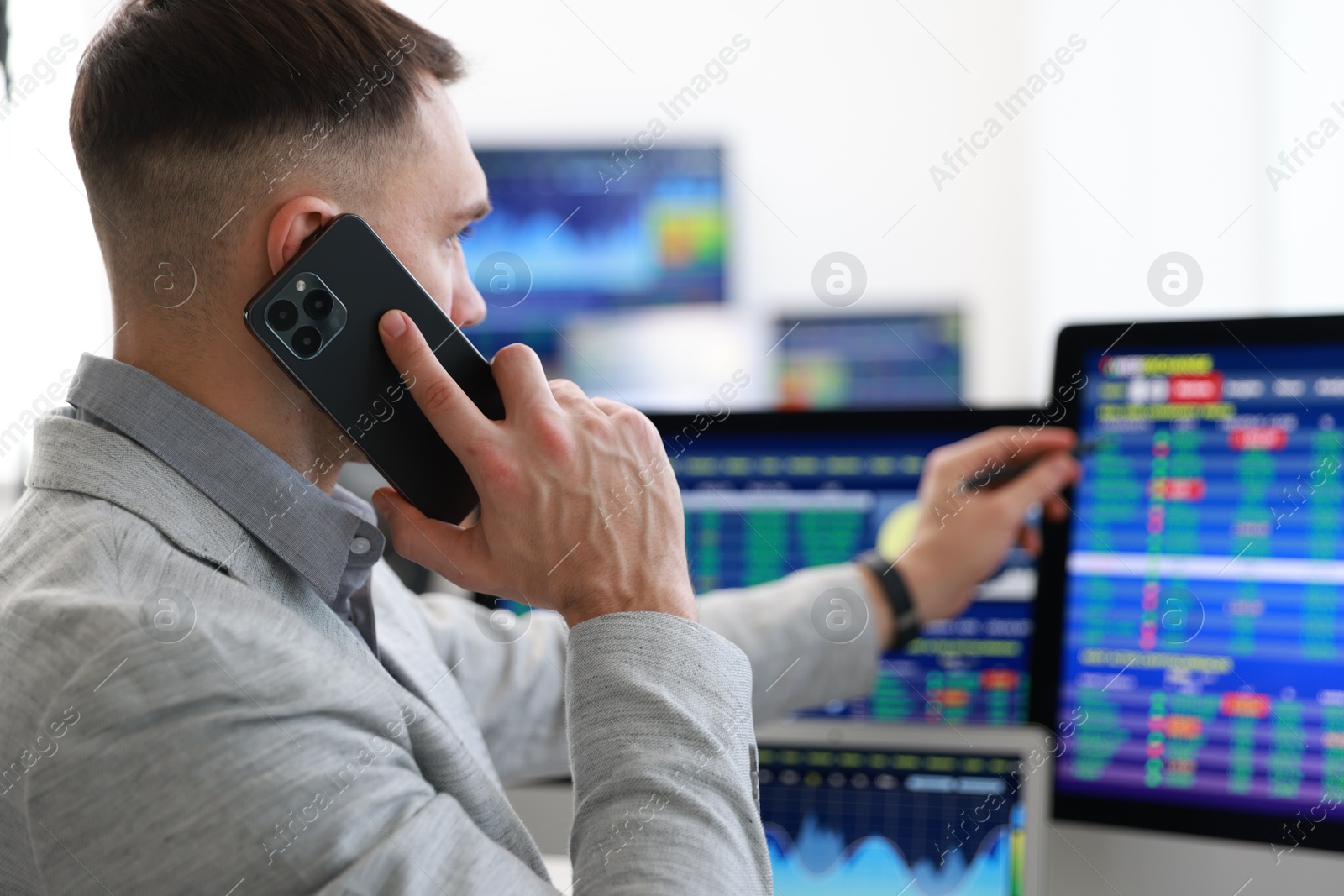 Photo of Financial trading specialist talking on phone in office