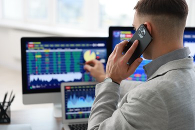 Photo of Financial trading specialist talking on phone in office