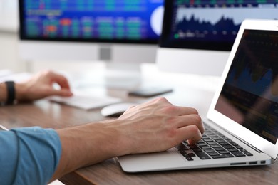 Photo of Financial trading specialist working on laptop at table in office, closeup