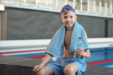 Photo of Boy with goggles and towel near swimming pool indoors