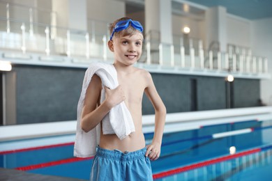 Photo of Boy with goggles and towel near swimming pool indoors