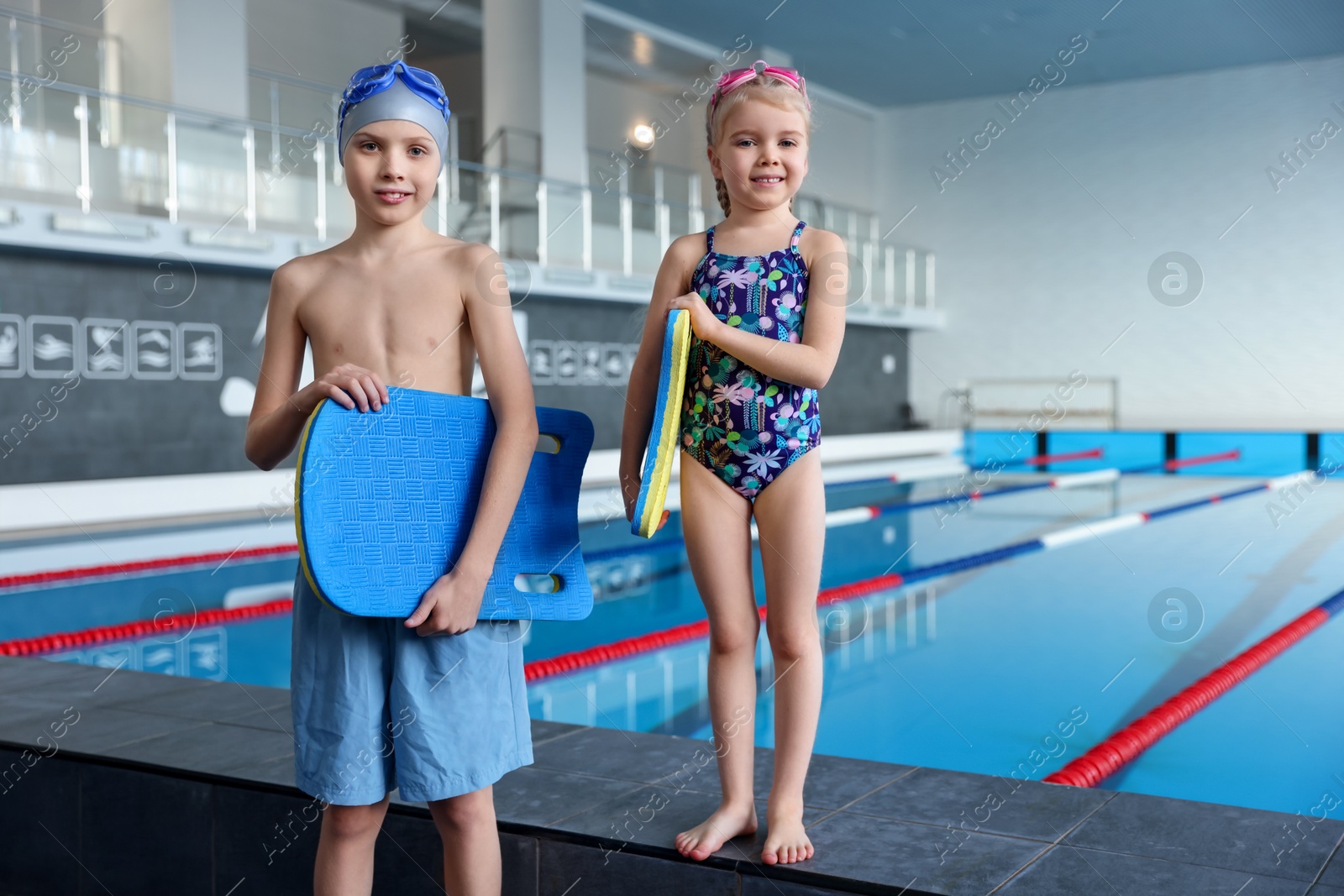 Photo of Children with goggles and kickboards near swimming pool indoors