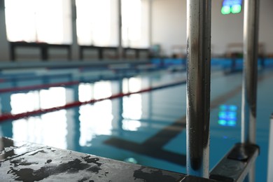 Photo of Swimming pool with clean water and ladder indoors, closeup