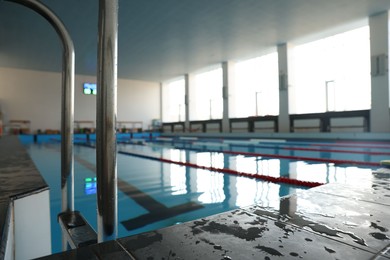 Photo of Swimming pool with clean water and ladder indoors, closeup